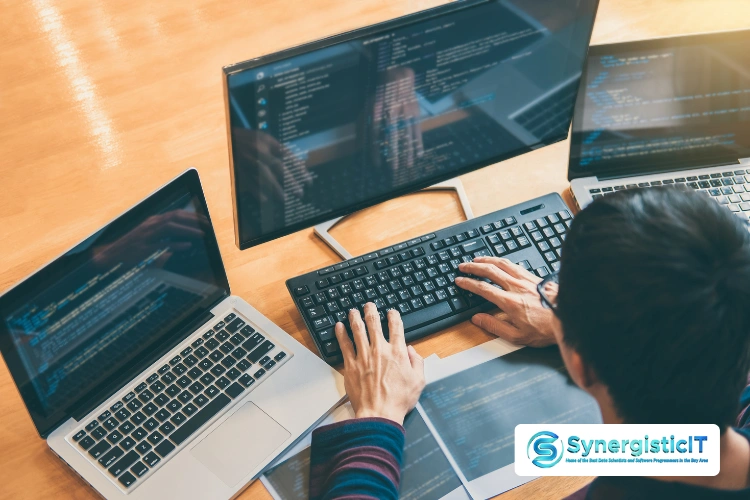 Multiple computer screens and keyboard displaying code, illustrating SOAP web services interview preparation.