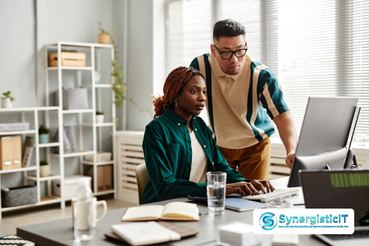 Two IT professionals reviewing PHP code on a computer screen, SynergisticIT software solutions and job